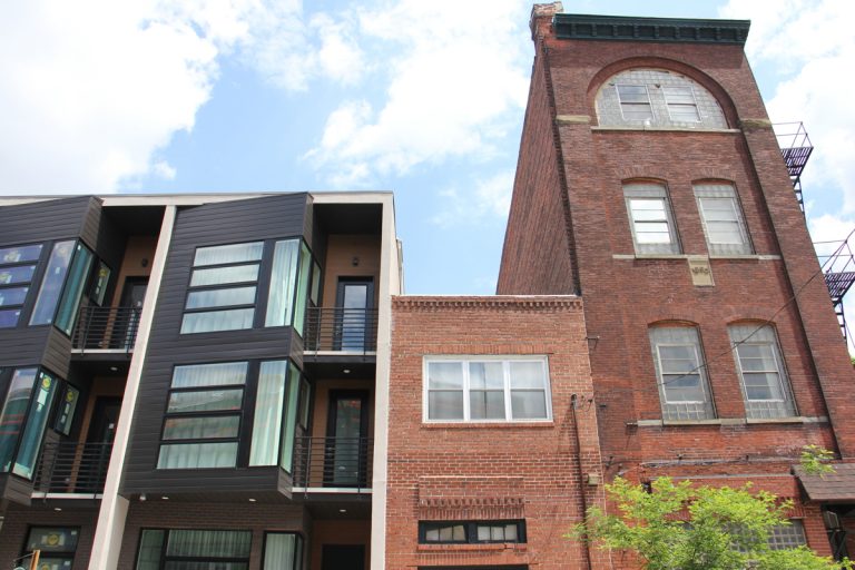A modern rowhouse stands next to old-fashioned brick residences.